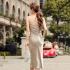 Robe longue satinée dos nu couleur champagne, fluide et élégante, inspirée du style vintage français, portée lors d’un événement en extérieur.