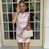 Femme élégante portant une robe satin courte rose poudré avec col haut et petit nœud décoratif