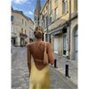 Femme portant une robe longue en satin jaune avec fente latérale et épaule dénudée