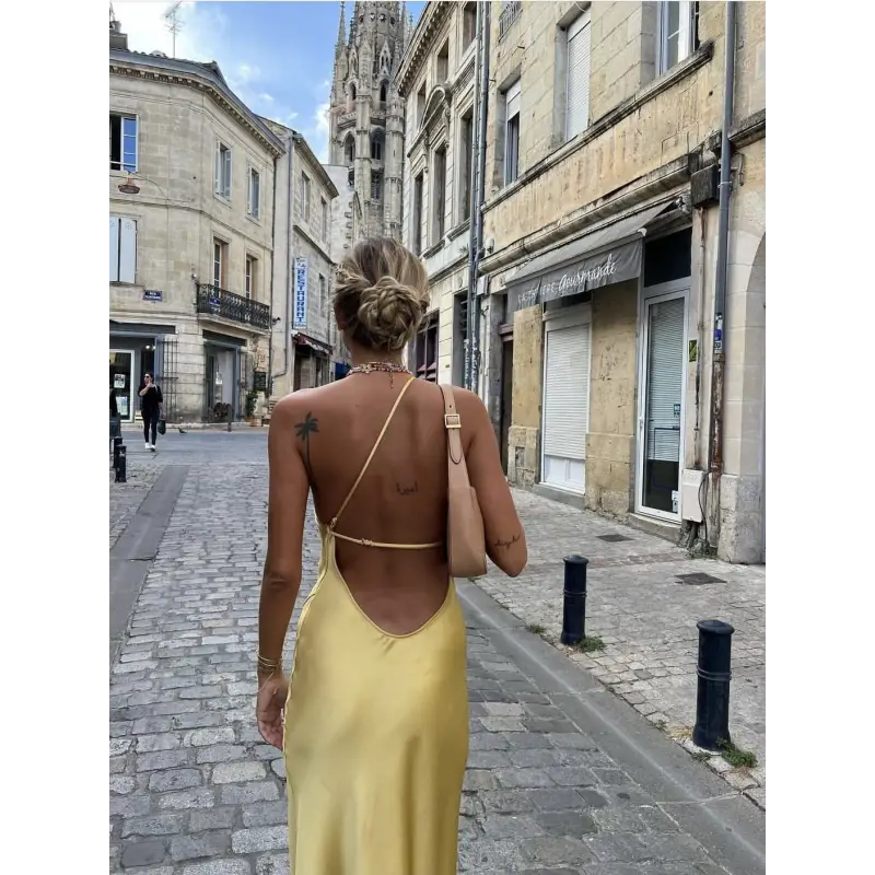 Femme portant une robe longue en satin jaune avec fente latérale et épaule dénudée