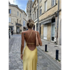Femme portant une robe longue en satin jaune avec fente latérale et épaule dénudée