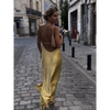 Femme portant une robe longue en satin jaune avec fente latérale et épaule dénudée