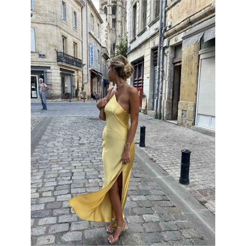 Femme portant une robe longue en satin jaune avec fente latérale et épaule dénudée