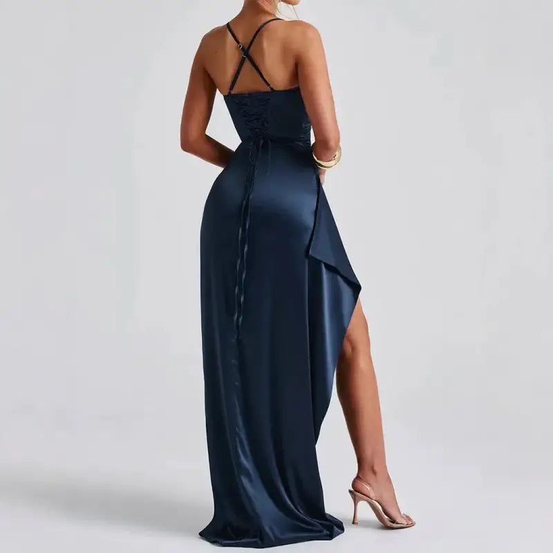 Femme portant une robe satinée bleu marine à dos nu et fente haute, silhouette élégante et sensuelle pour une soirée chic.