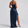 Femme portant une robe satinée bleu marine à dos nu et fente haute, silhouette élégante et sensuelle pour une soirée chic.